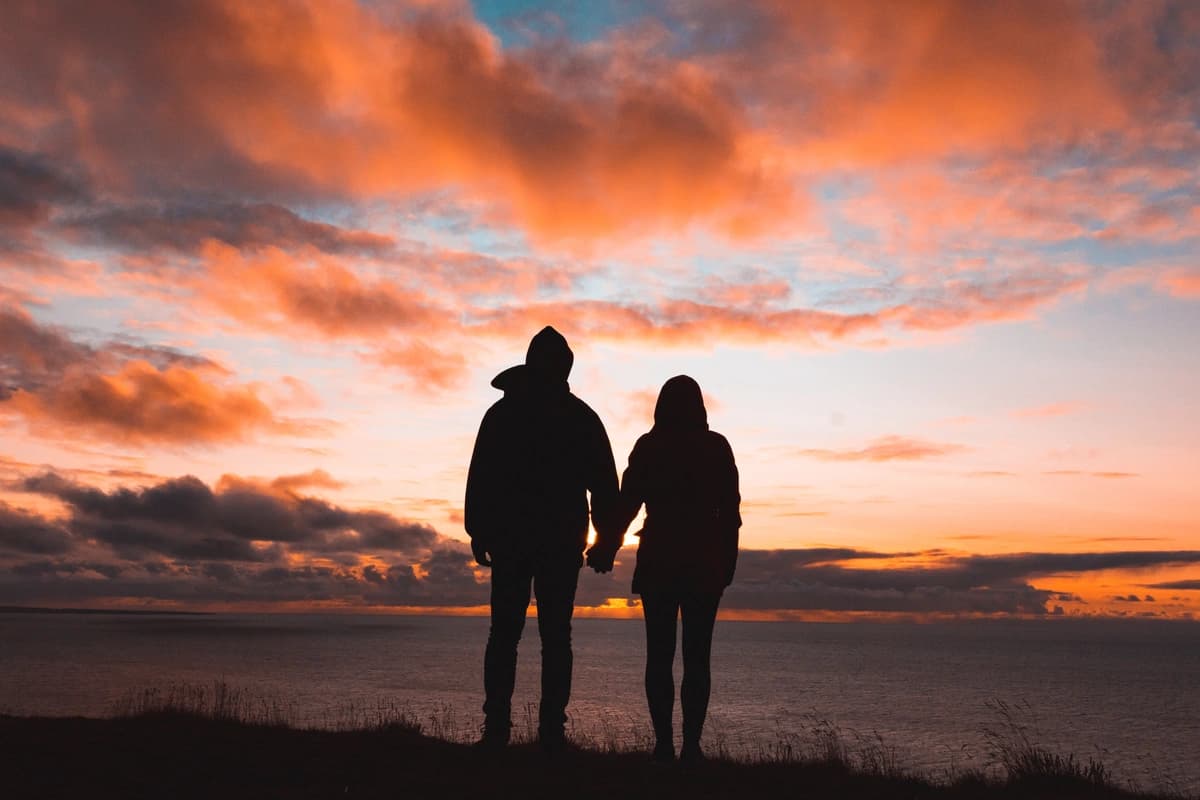 Couple holds hands outside at sunset