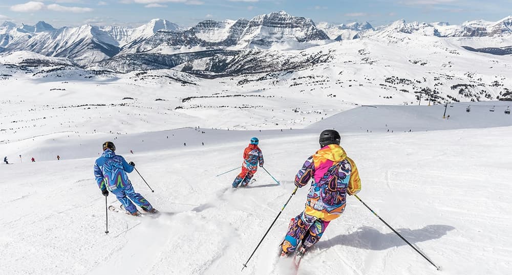Three skiiers on top of a snowy slope