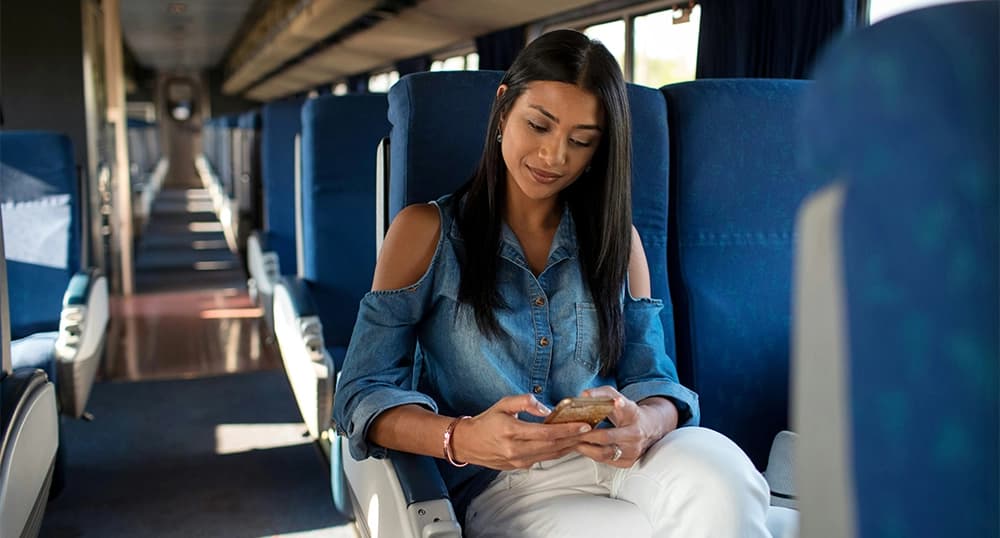 Woman traveling on a train accessing virtual doctor visits on her phone.
