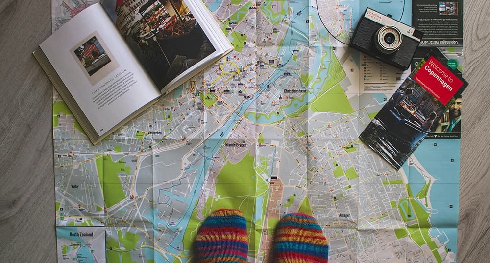A person standing on a map with a camera and pamphlets.