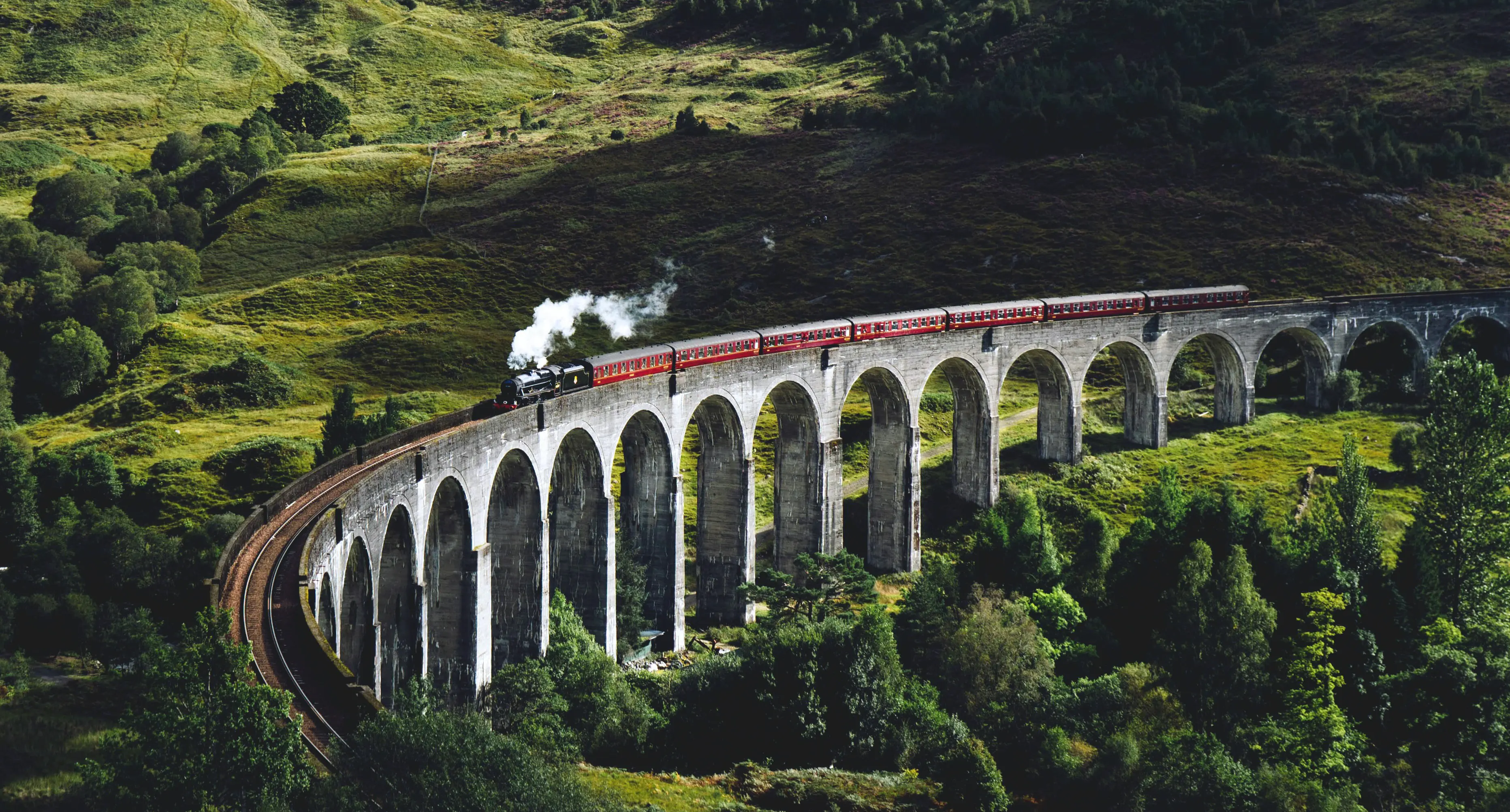 Train traveling on an aqueduct through a scenic valley by Jack Anstey on Unsplash
