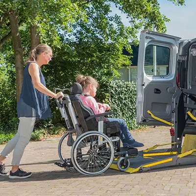 Female with travel insurance boarding mini-van in wheelchair.