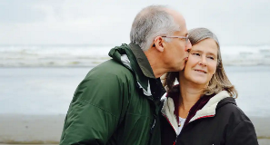 Man kisses his wife on the cheek beachside