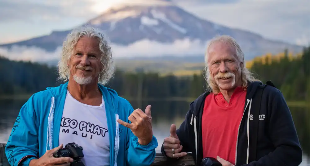 Two men pose for a photo in front of volcano