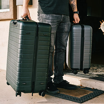 Man picking up luggage at a door.