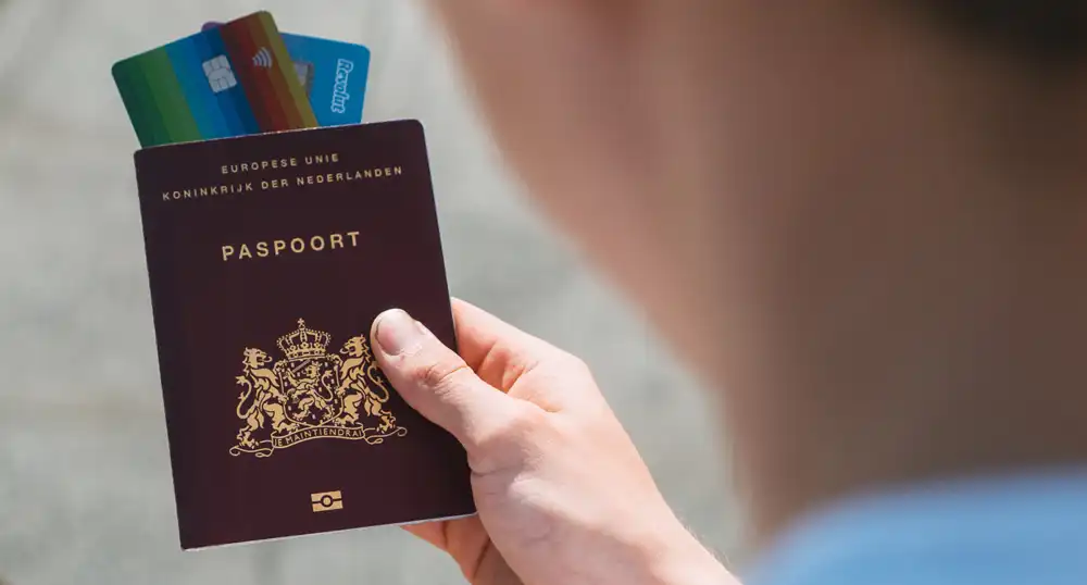 Man holding passport with credit cards sticking out top