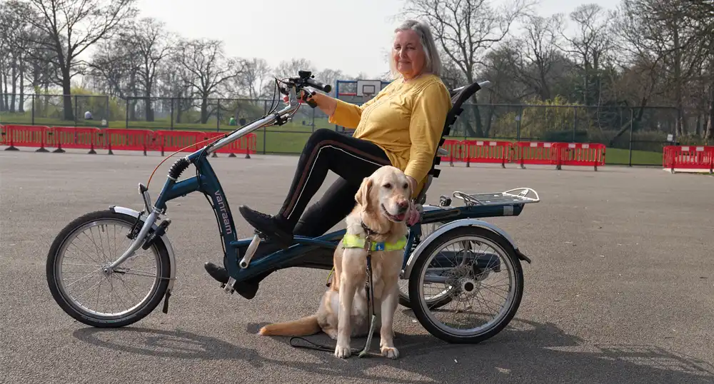 Woman rides adaptive bicycle with service dog