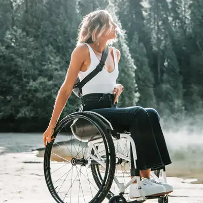 Woman in a wheelchair overlooks forest lake