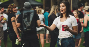 Woman holding red drink cup at outdoor festival.