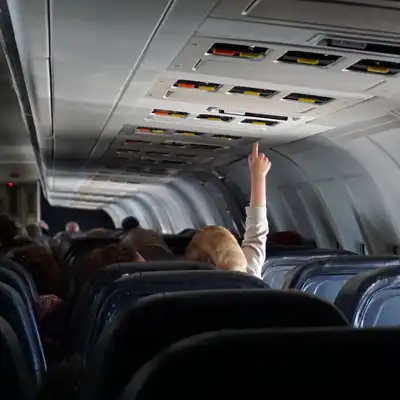 Toddler pushes overhead buttons on an airplane
