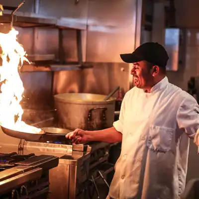 Chef sautes food with big flames coming off pan