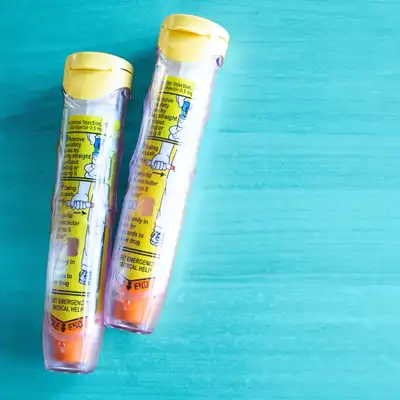 Two EpiPens on a blue background