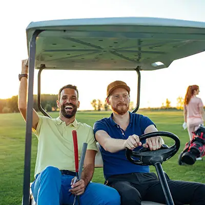 People driving golf cart at golf course.