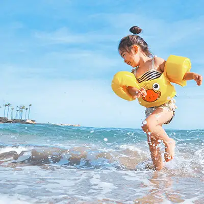 Child wearing floaties splashing water at the beach in Florida.
