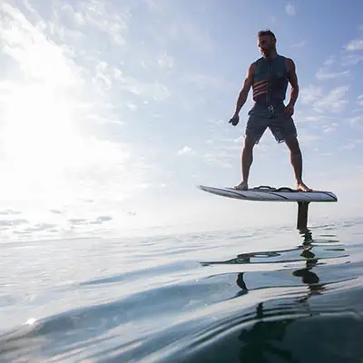 Man surfing on electric surfboard over the water.
