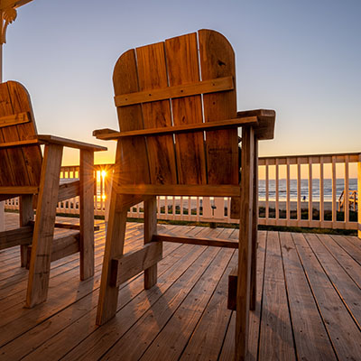 Chairs on a deck with a beach view.