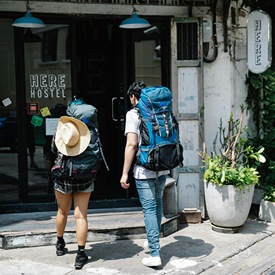 Couple of travellers with backpacks entering hostel