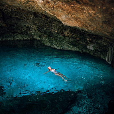  woman swimming under cave