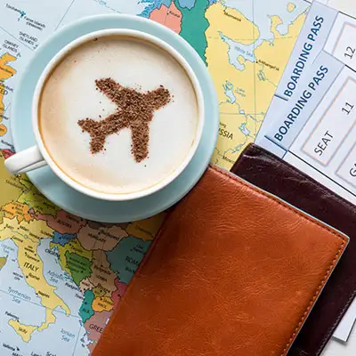 Airplan in chai tea latte, on top of boarding passes and map of Europe.