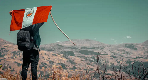 Man holds up Peruvian flag overlooking desert
