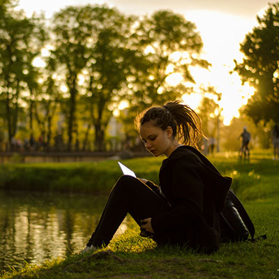 Student sitting by a pond.