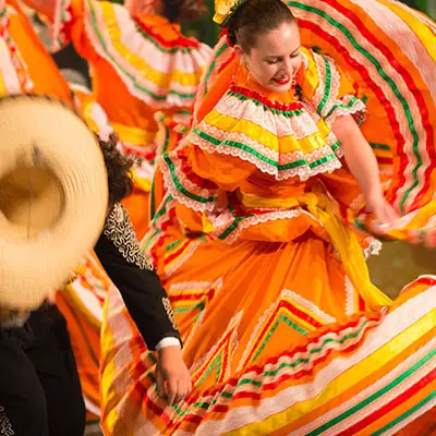 Hispanic woman dancing for a celebratory parade in Mexico.