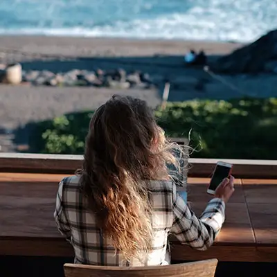 Girl working remotely from chilly beach.