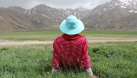 Woman-sitting-on-the-grass-in-front-of-mountains