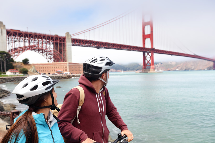 Young couple on guided bicycle sight seeing tour looking at Golden Gate Bridge